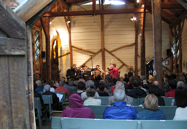 wooden building that is a concert hall, with musicians playing and audience backs 