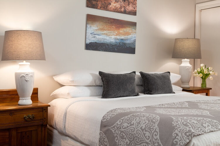 King-sized bed with hoot linens and gray pillows and coverlet.