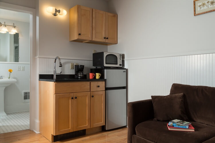 A brown counter with black top, sink and refrigerator.