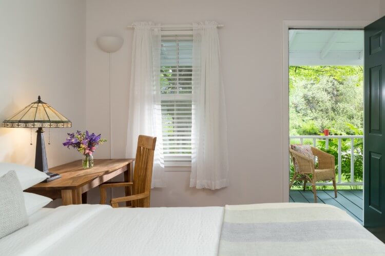 Bed with a desk and window with door opening to trees.