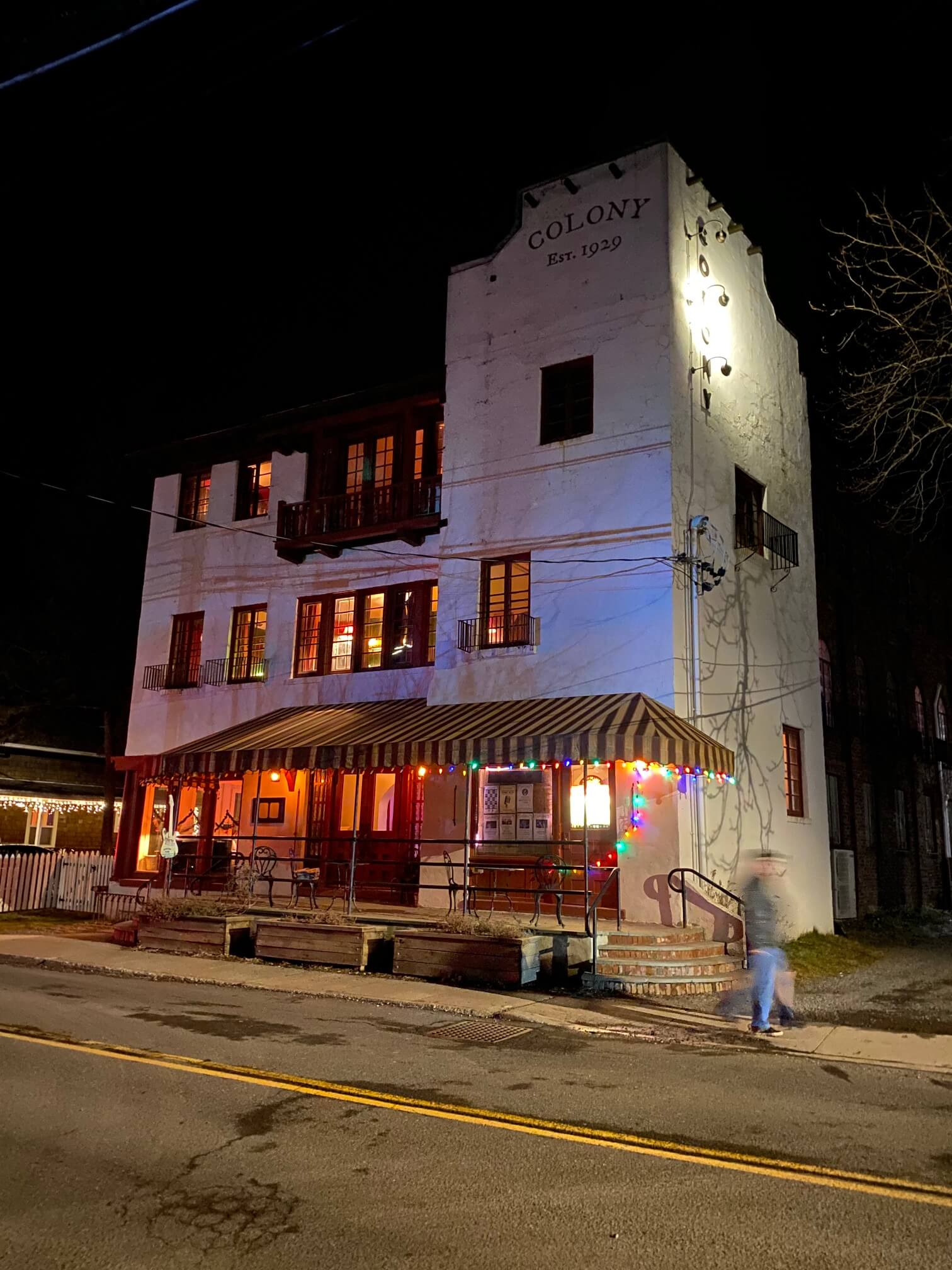 a tall white, stucco two-story building with red awanings