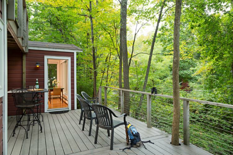 Spacious raised deck with small dining table for two and four chairs overlooking the wooded lush green view