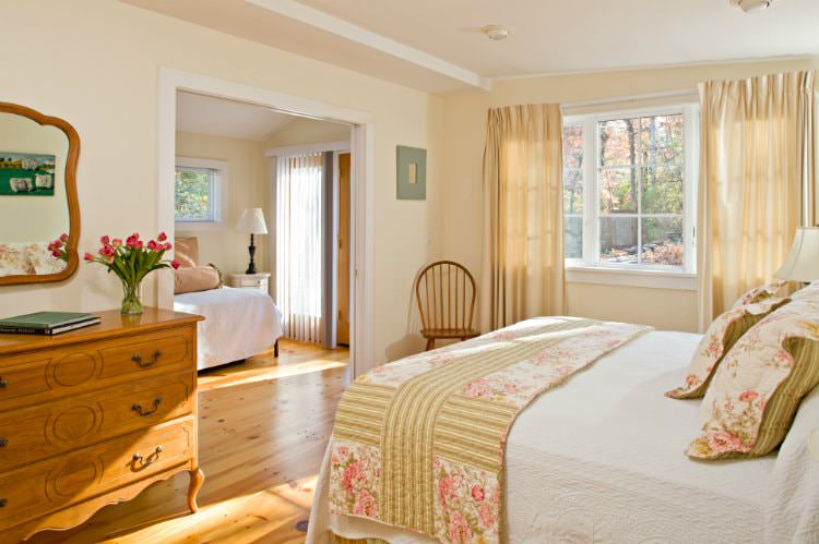 Warm and cozy beige and white adjoining rooms with wood floors, lots of natural light, and white covered beds
