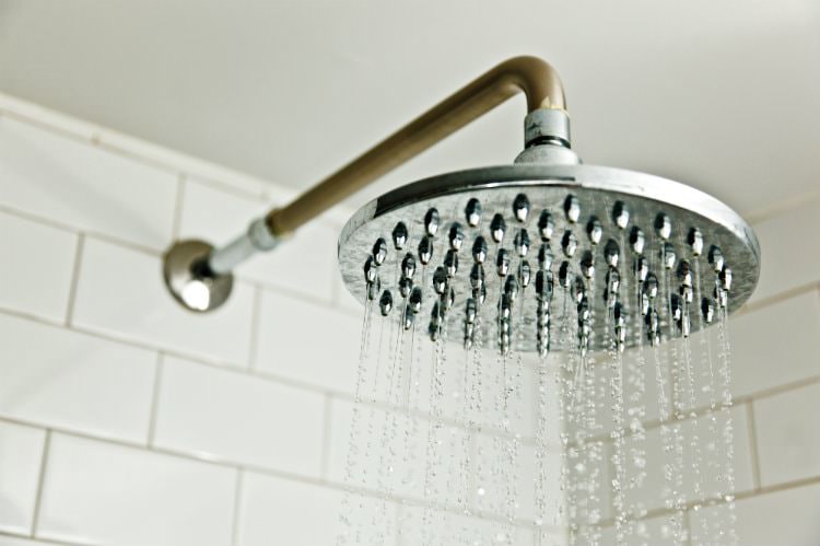 Close up view of rain shower head in white tiled shower