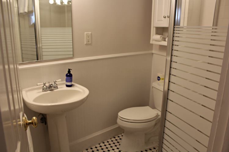 Beige and white bathroom with pedestal sink and tiled shower