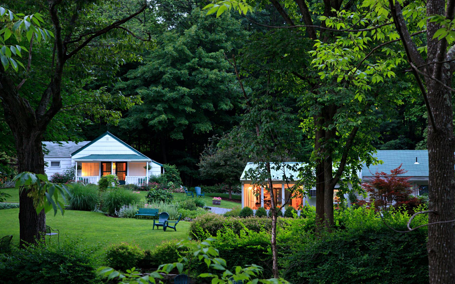 White cottages surrounded by dark, lush green grass, shrubs, plants and trees