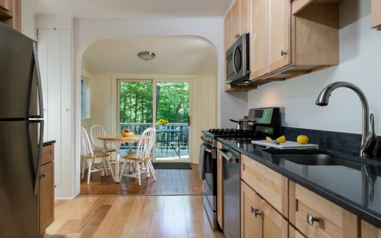 A black kitchen counter with a dining room table with sliding glass doors that open to the patio.