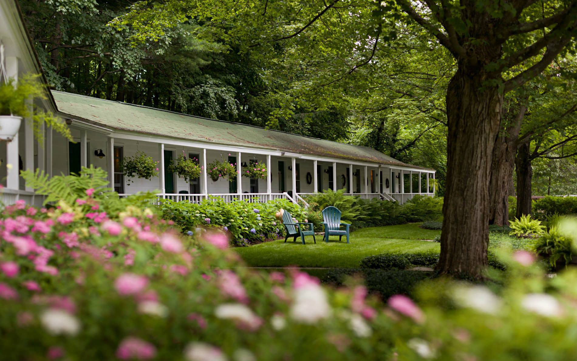 View of the white inn surrounded by lush green trees and lawn